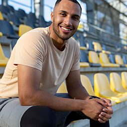 A man is sitting on a stadium chair after exercising.