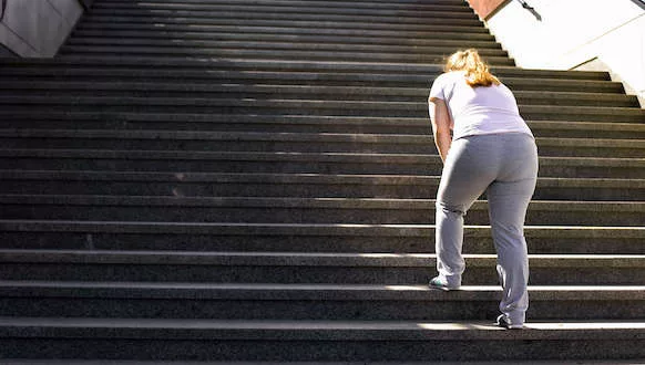 A photo of a person struggling to walk up steps
